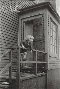 Betty (Pelley) Mason climbing the railing of her row house on Main Street.