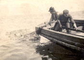 Two men in a boat hauling a cod bag