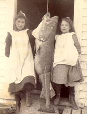 Two girls standing by a large codfish, Labrador